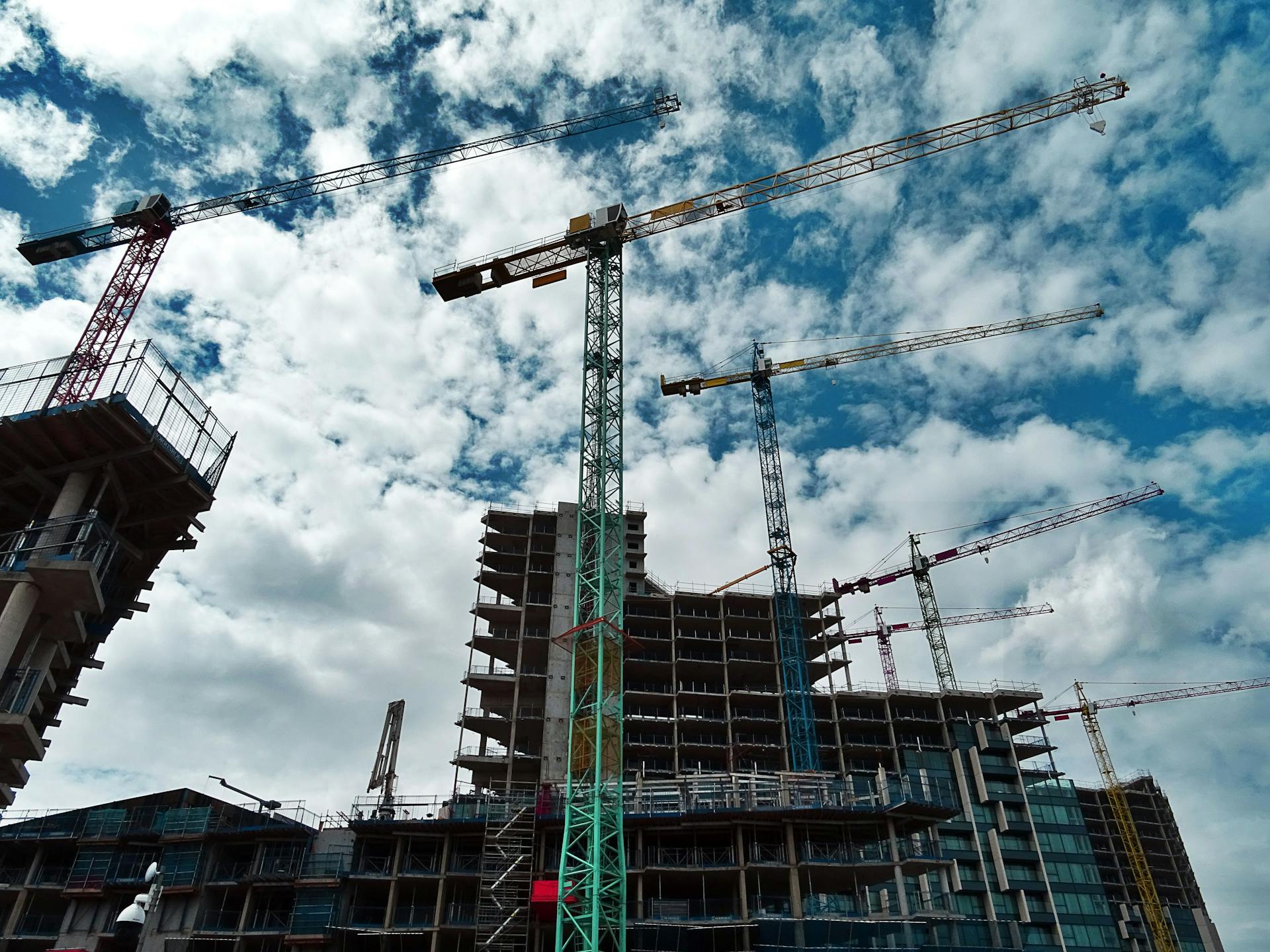 Construction site at golden hour with cranes silhouetted against a warm sky
